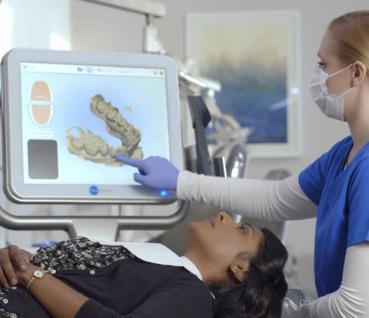 Dental team member showing a patient digital models of their teeth on a screen