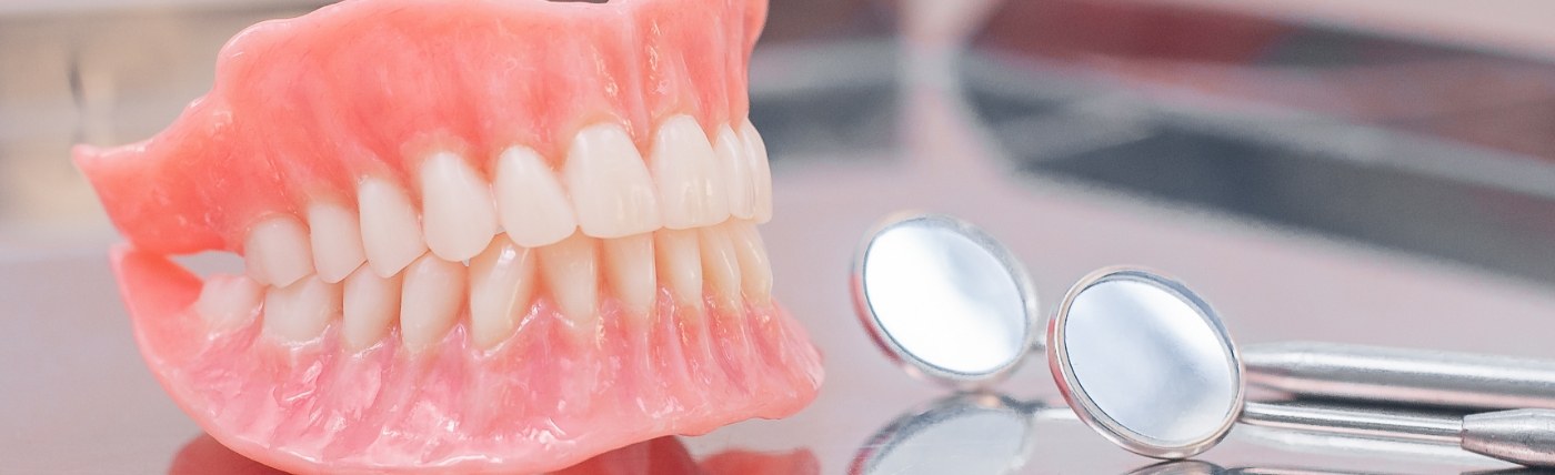 Full dentures in Waco on table next to dental mirrors