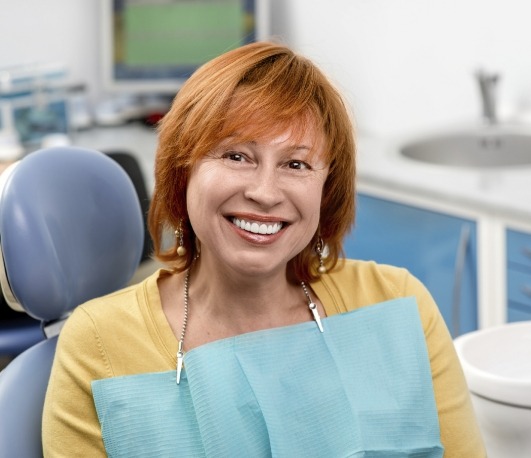 Older woman with orange hair smiling in dental chair
