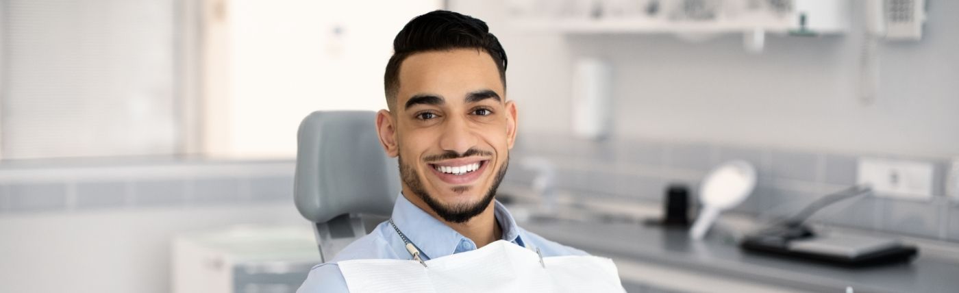 Man smiling in dental chair after replacing missing teeth in Waco