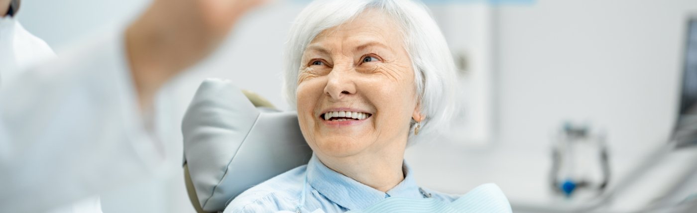Senior woman in dental chair smiling at her Waco dentist