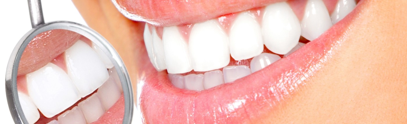 Close up of dental mirror reflecting bright smile after teeth whitening in Waco
