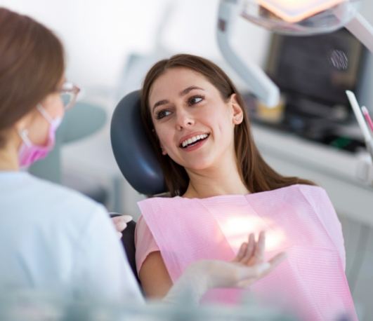 Woman in dental chair talking to her dentist