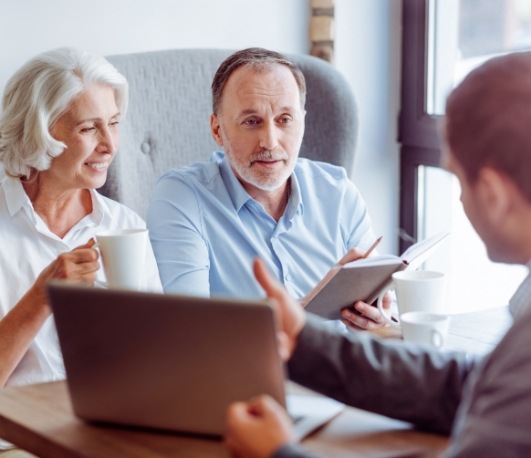 Senior couple talking to man across desk