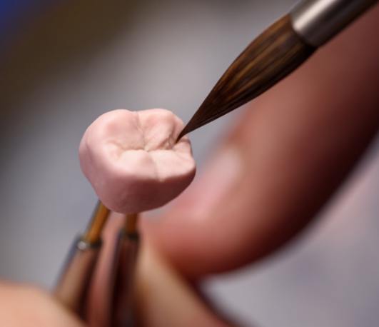 Ceramist carefully designing a dental crown