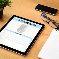 Dental insurance form displayed on tablet next to notebook