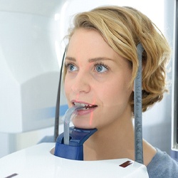 female dental patient standing in dental scanning machine
