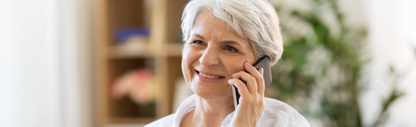 Older woman using cell phone to contact Waco dental office