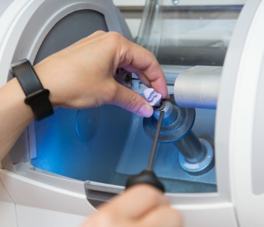 Dentist placing a small ceramic block in a same day dental crown machine