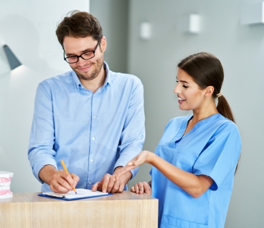 Dental team member showing a patient where to sign on a clipboard