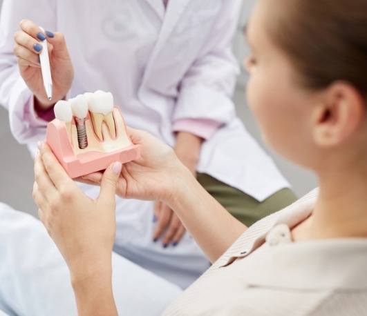 Dentist showing a dental implant model to a patient