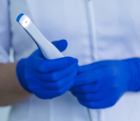 Dental team member holding thin white intraoral camera