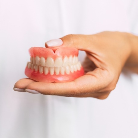 Hand holding a set of full dentures