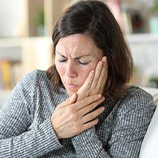 Woman with a toothache in Waco holding her cheek