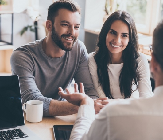 Man and woman sitting across desk from their dentist