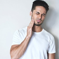 A man holding his mouth in pain.