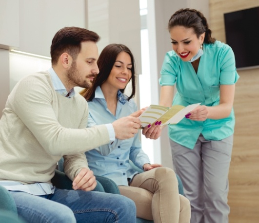 Dental team member showing a pamphlet to two patients