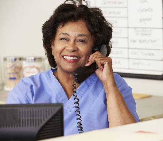 Dental team member sitting at desk and answering phone