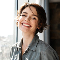 Woman with dental implant in Waco, TX smiling at window