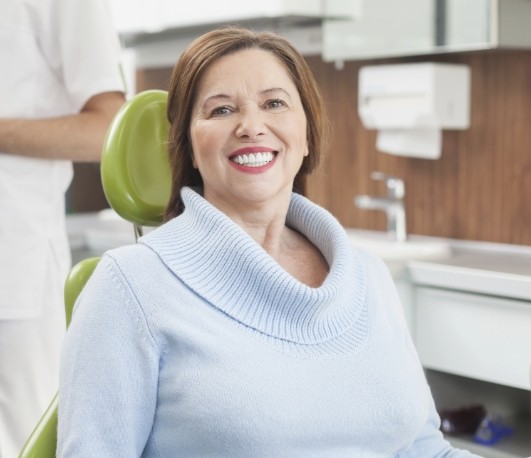 Woman in light blue sweater smiling in dental chair