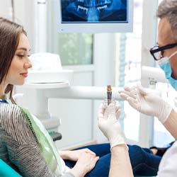 implant dentist in Waco showing a dental implant to a patient