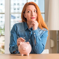 Woman with piggy bank for cost of Invisalign in Waco