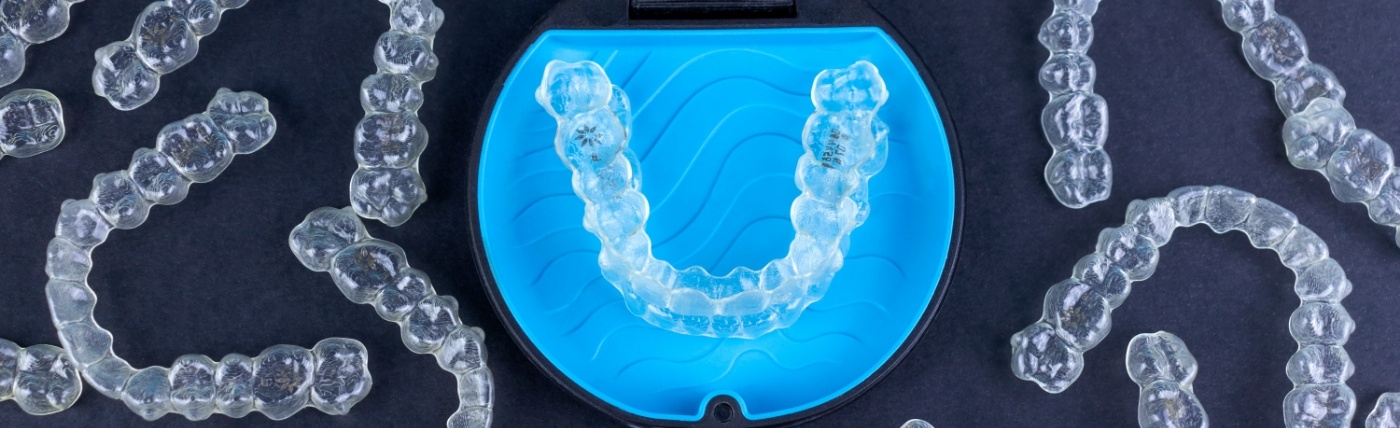 Several Invisalign clear aligners in Waco on desk with two in their storage case
