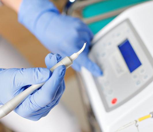 Dentist holding a dental laser and pressing a button on a machine