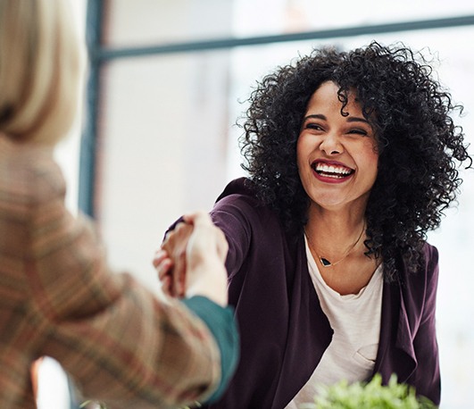 Two women smiling while shaking hands