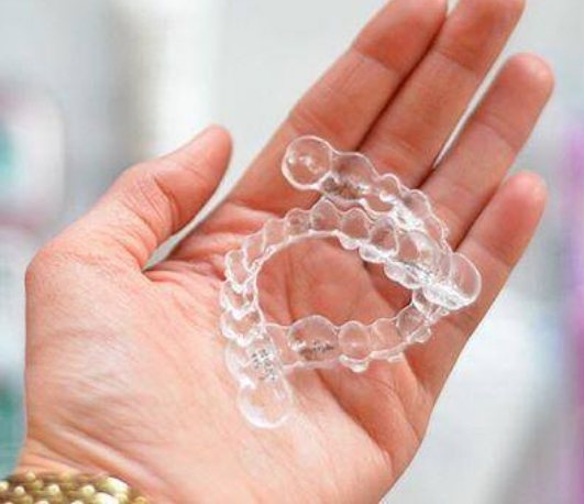 Hand holding two Invisalign clear aligners