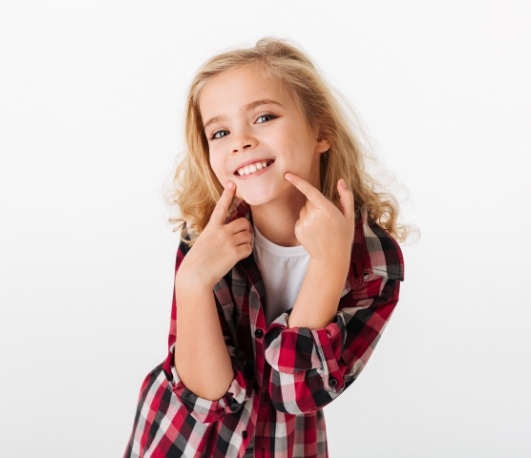 Young blonde girl pointing to her smile