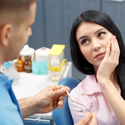a patient holding their cheek at the dentist’s office