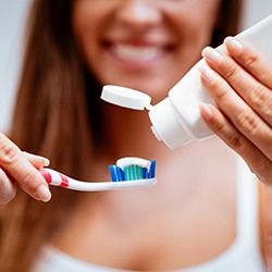 woman putting toothpaste on toothbrush