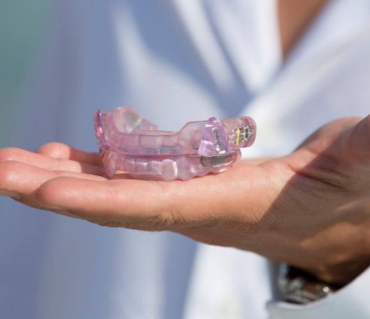 Dentist holding a light purple oral appliance for sleep apnea treatment