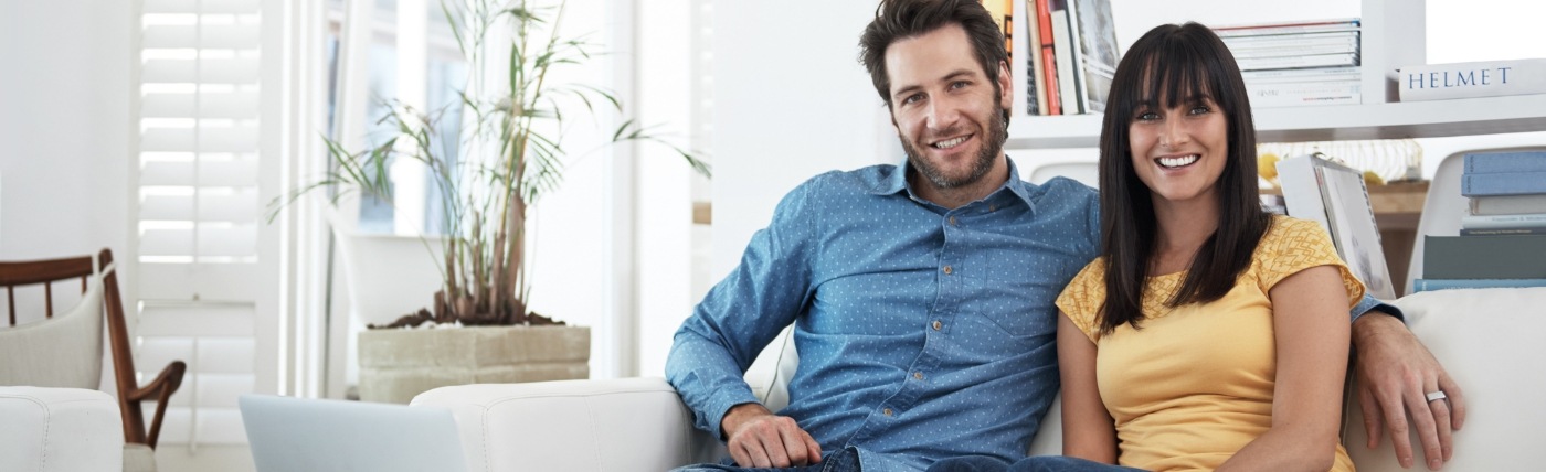 Smiling man and woman sitting on couch together