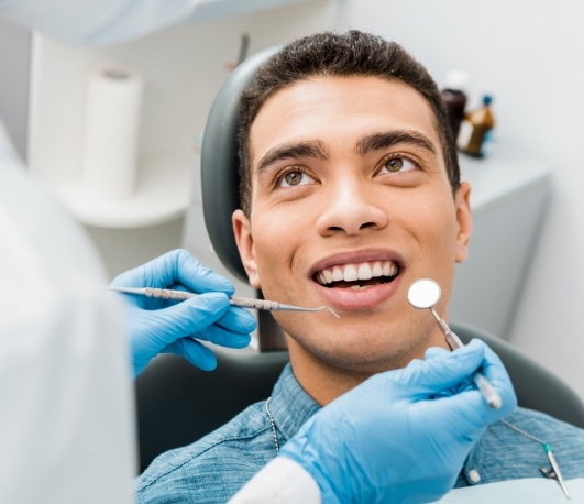 Man in dental chair looking at his cosmetic dentist