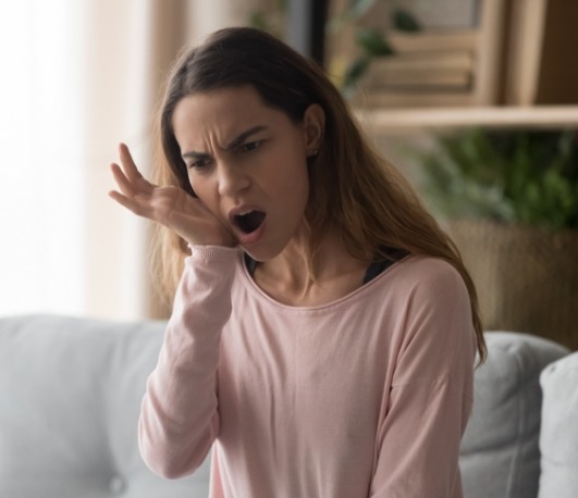 Woman holding her jaw in pain needing T M J treatment in Waco