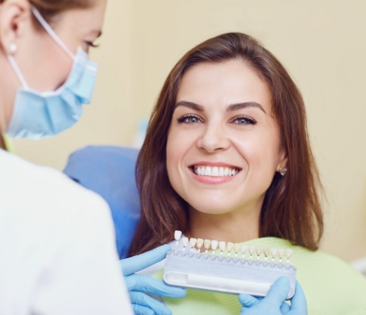 Dentist holding shade guide next to smiling patient