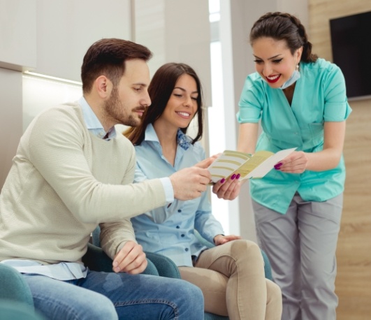 Dental team member showing a pamphlet to two patients