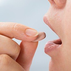 woman putting pill in mouth