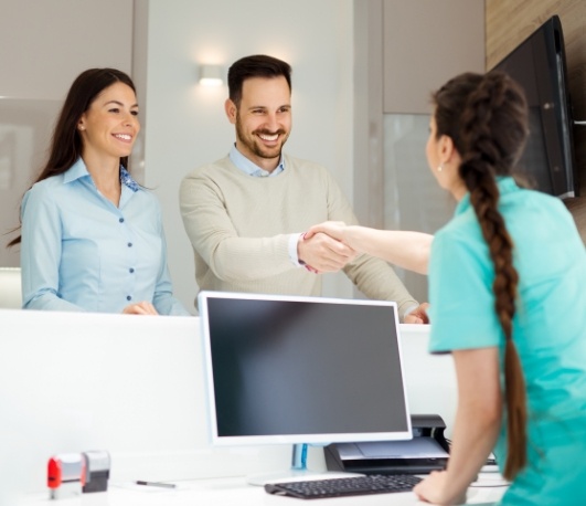Man shaking hands with dental office receptionist
