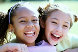 Two girls smiling after vising their family dentist