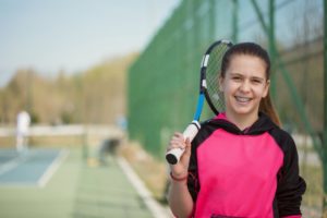 young girl with braces in Waco holding a tennis racket 