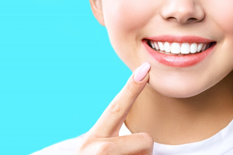 an up-close image of a person pointing to their whitened smile