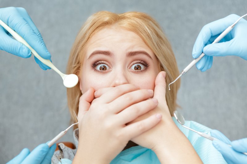 Scared woman protecting her mouth from dental tools