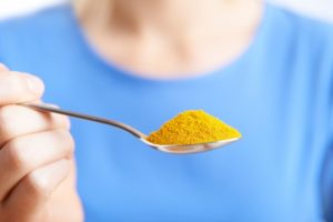 woman holding spoonful of turmeric