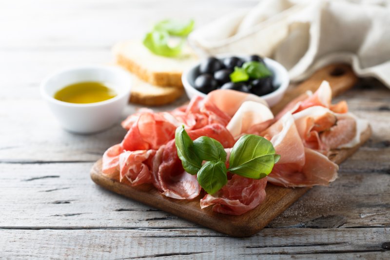 A charcuterie board with nutritious meat, olives, and soft bread