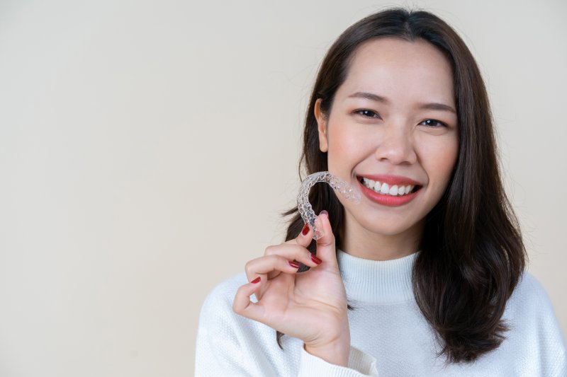 patient holding Invisalign tray and smiling 