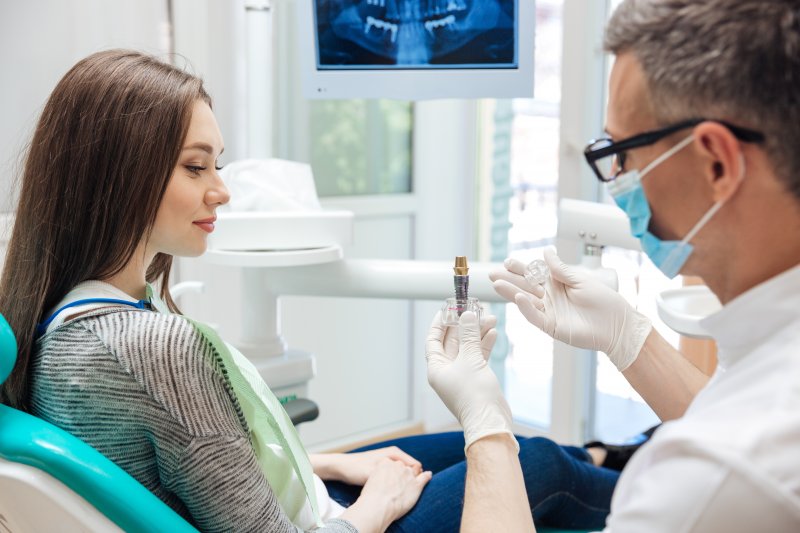 A dentist showing a dental implant to his female patient