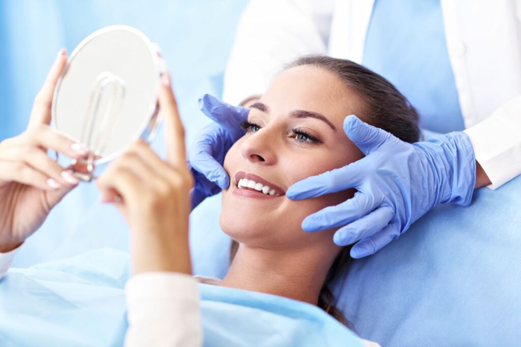 A woman in a dental chair looking in the mirror at her smile
